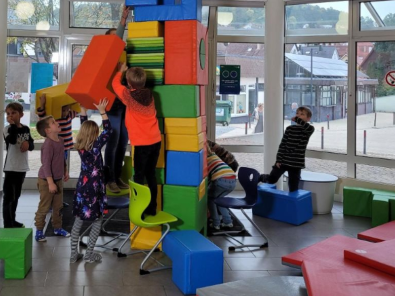 Spielende Kinder die mit Bauteilen einen Turmbauen