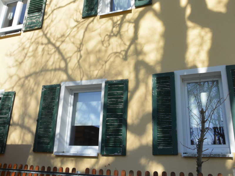 Beigegelb erstrahlt die Giebelwand des Alten Schulhauses in Neuhengstett. Die vielen Fenster tragen dunkelgrüne Fensterläden.