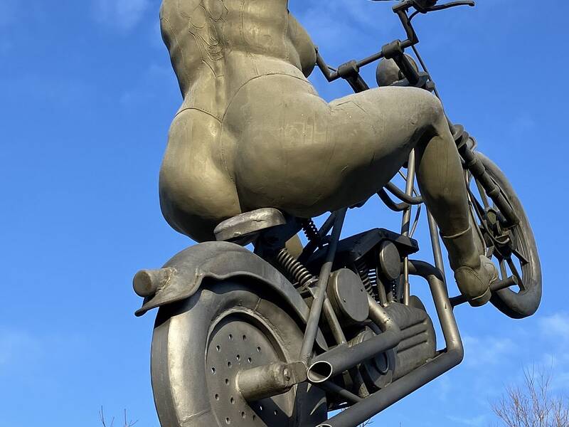 Figuren-Trilogie des Künstler Peter Lenk an der Liebenzeller Straße in Hirsau. Diese Figur stellt eine nackte Frau auf einem Motorrad dar, dessen Vorderrad in der Luft schwebt.