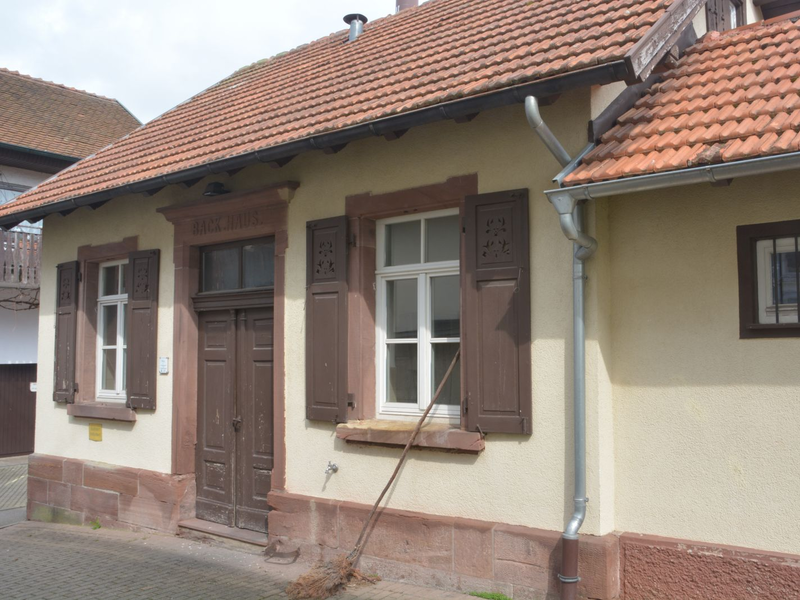 Ein Reisigbesen steht vor dem Backhasu Ottenbronn mit seiner gewaltigen Holztür.