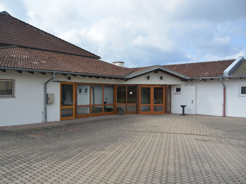 Mit grauen Steinen gepflasterter Breich vor dem Eingang zur Mehrzweckhalle Ottenbronn.