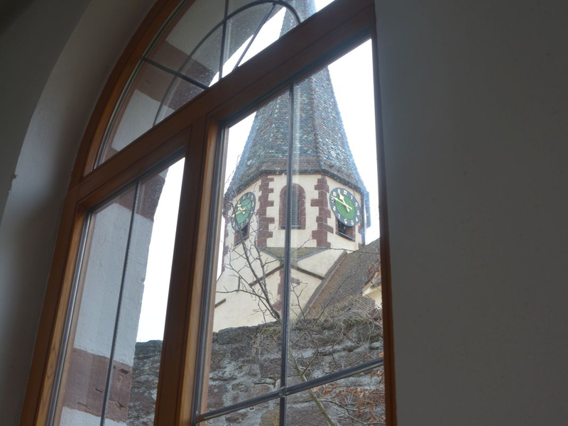 Druch ein Rundbogenfenster lugt der Turm der nahen Markuskirche herein.