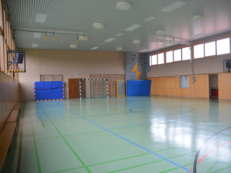 Blaue Matten stehen in der Turn- und Festhalle an der Wand neben den Sprossenwänden.