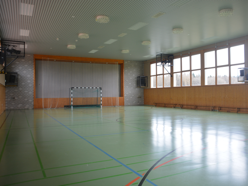 Durch die große Fensterfront fällt Licht auf den hellgrünen Sportbnoden mit seinen Markierungen.