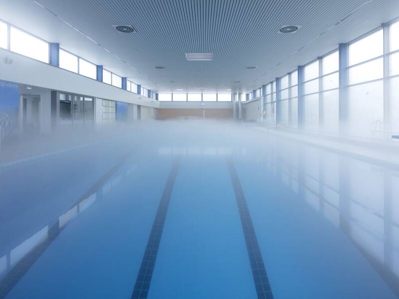 Feiner Nebel wabert über dem türkisblauen Wasser des Schwimmerbeckens.