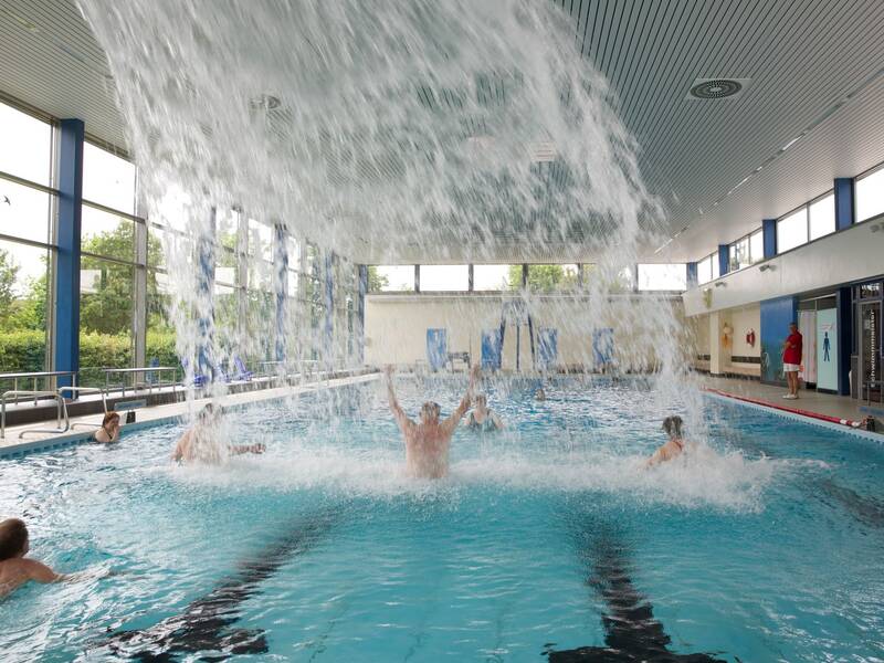 Wassergymnastik im großen Becken des Hallenbads. Davor ergießt sich der Wasserfall des Massagestrahls.